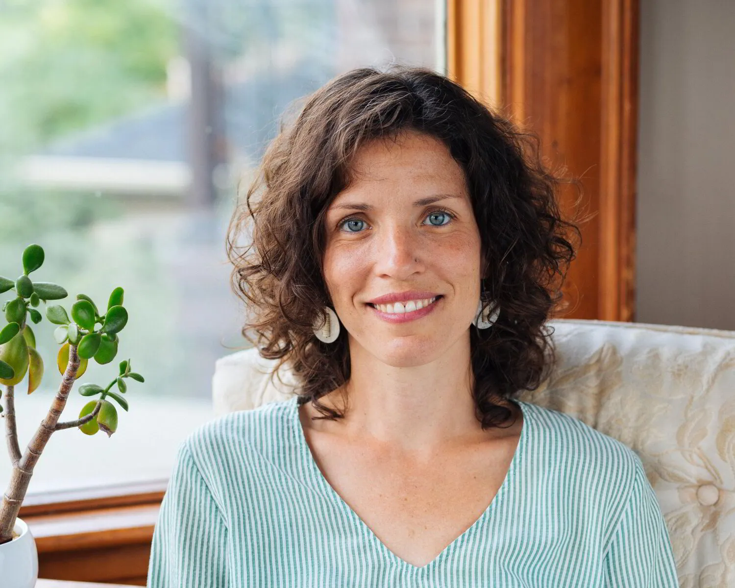 Caitriona Keown, Therapist, sits in mint coloured shirt by window