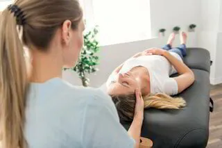 physiotherapist helps woman stretch neck