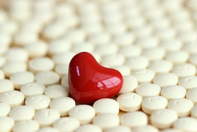 A heart shaped pill in a bed of white round pills.
