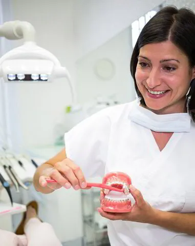 Smiling Female Doctor while holding denture in clinic