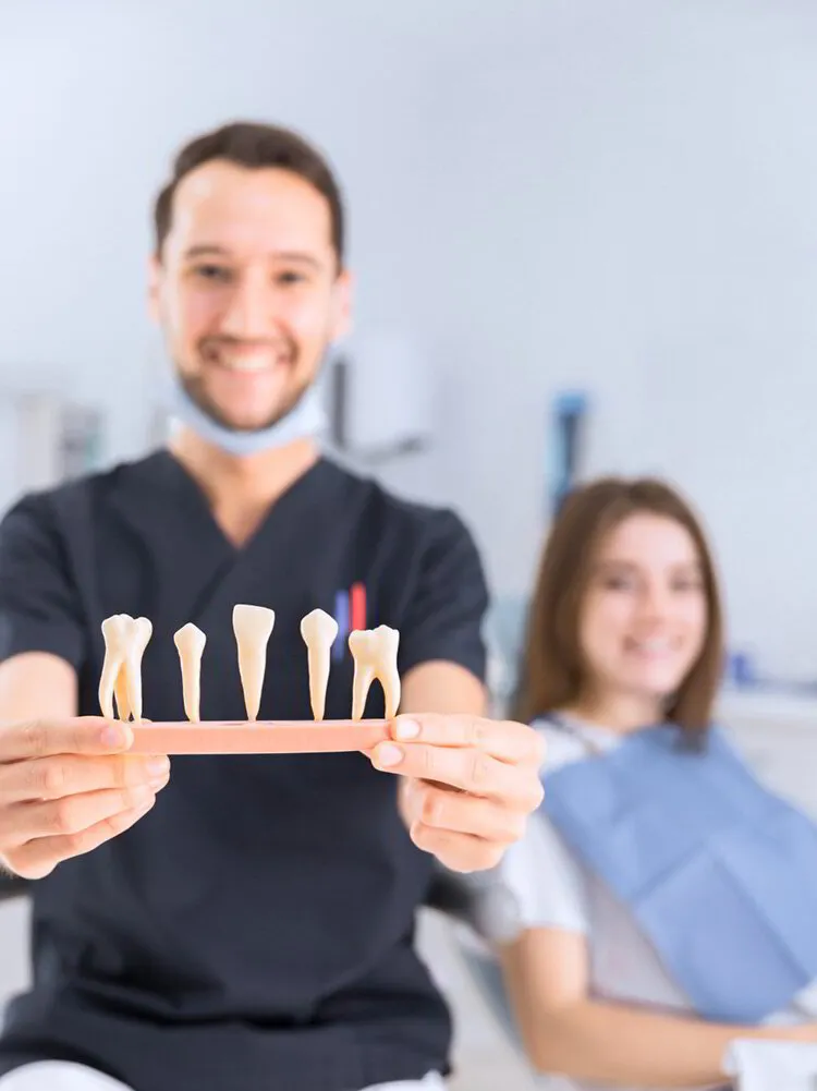 smiling male dentist showing partial teeth behind patient in dental clinic