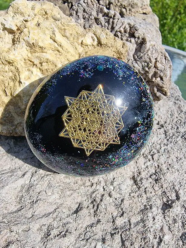 Oval "sten" i guld, svart och glittermix med symbol i guld av en 64 Tetrahedron stjärna