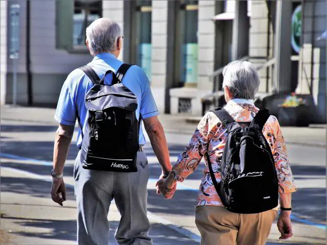 Un couple d'anciens se promènent en ville se tenant par la main.