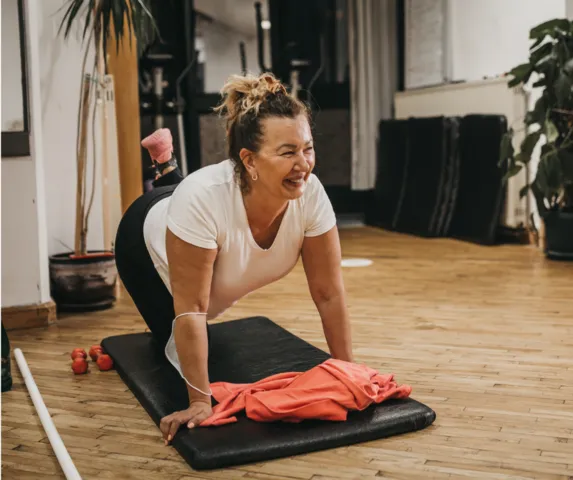 woman exercising on floor mat and smiling