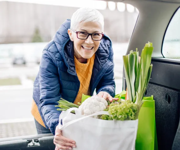 woman smiling putting groceries into her car
