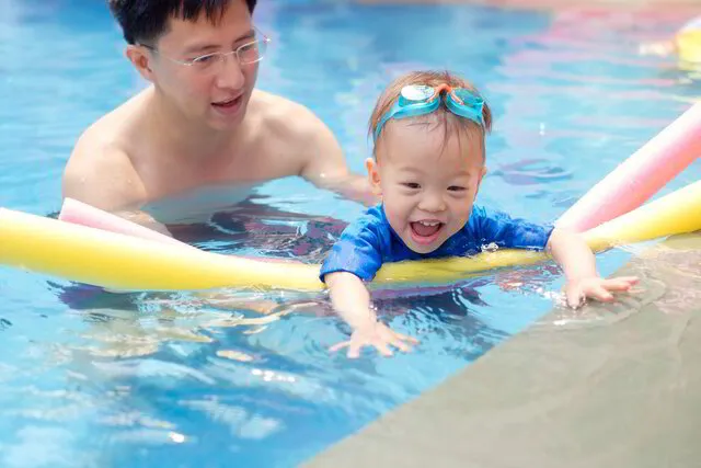 Happy Infant playing in the water - Baby Swimming Lessons Singapore