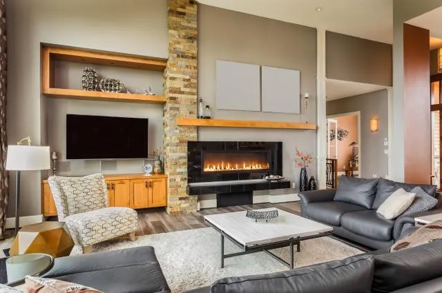 photo of living room with fireplace, cozy lounge chairs and couches, and brick accent wall
