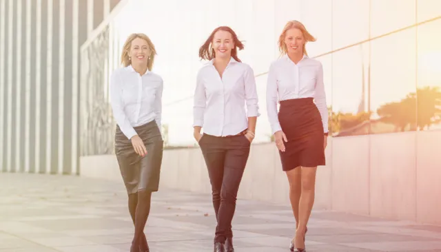 drei selbstbewusste Geschäfts-Frauen laufen beschwingt auf uns zu.