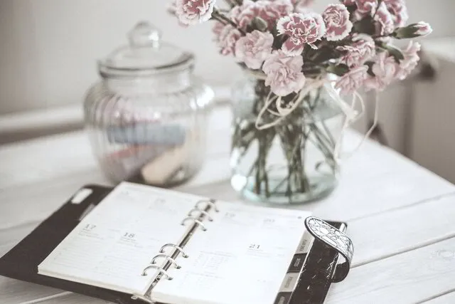 Closeup of day planner and flowers on wooden table