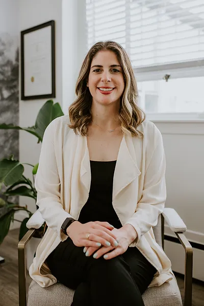 Dr. Catherine Multari, ND in an office setting, dressed in business casual with a plant in the background.