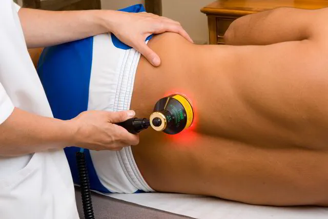 practitioner administering cold laser treatment on patient's back