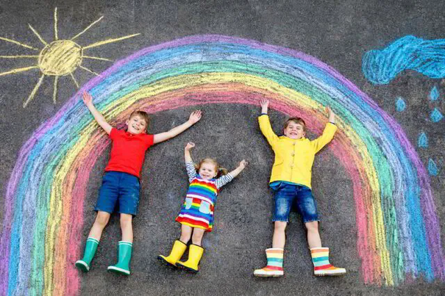 children lying on ground with a rainbow and sun drawn in chalk at Discovery Christian School, in Effingham, IL