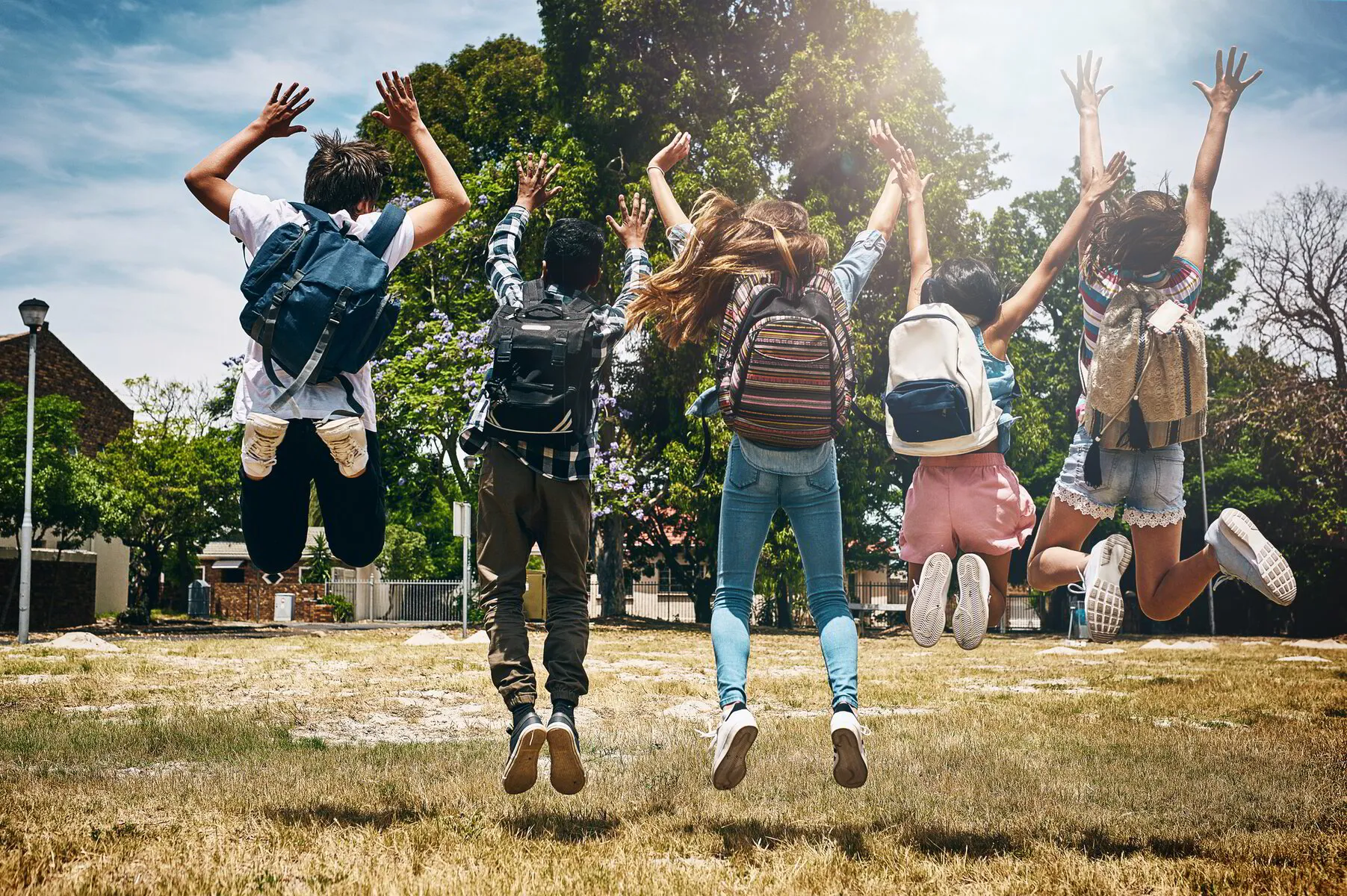 school children jumping with backpacks on