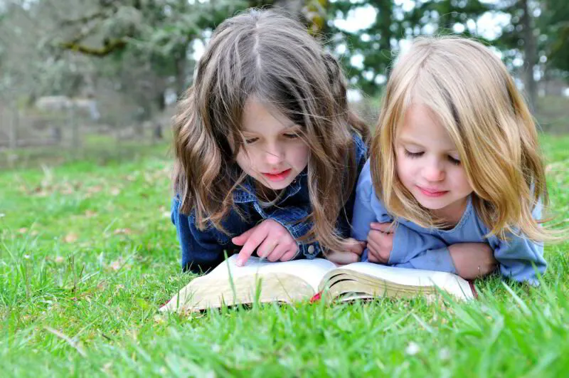 children reading the Bible on grass at Discovery Christian School in Effingham IL