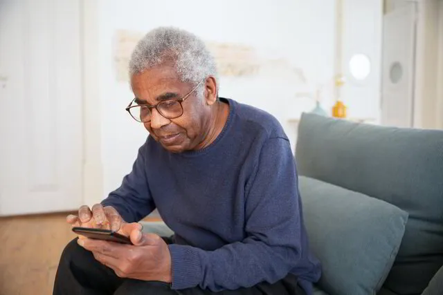 Ein älterer Herr schaut auf sein Smartphone.