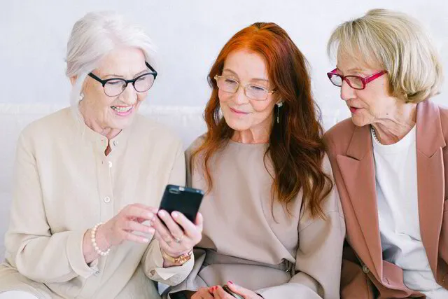 Drei Frauen schauen auf ein Smartphone.