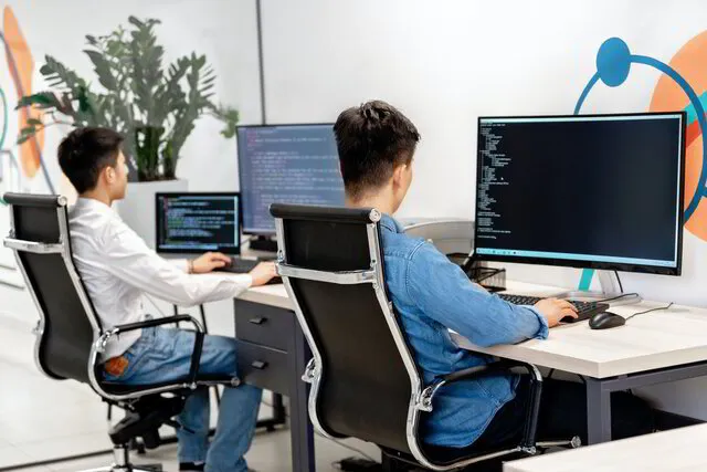 Zwei männliche Personen arbeiten an Computern.
