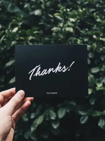 A hand holding up a thank you card.