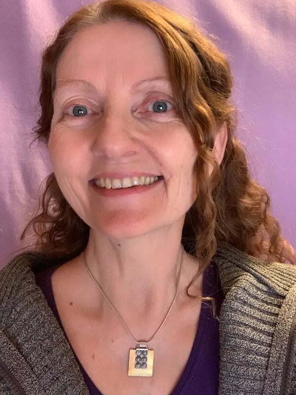 A smiling woman with curly hair against a purple background.