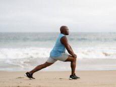 A man doing a lunge on a beach
