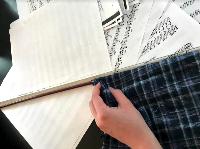 A person cleaning the wood of the violin bow with a cloth.