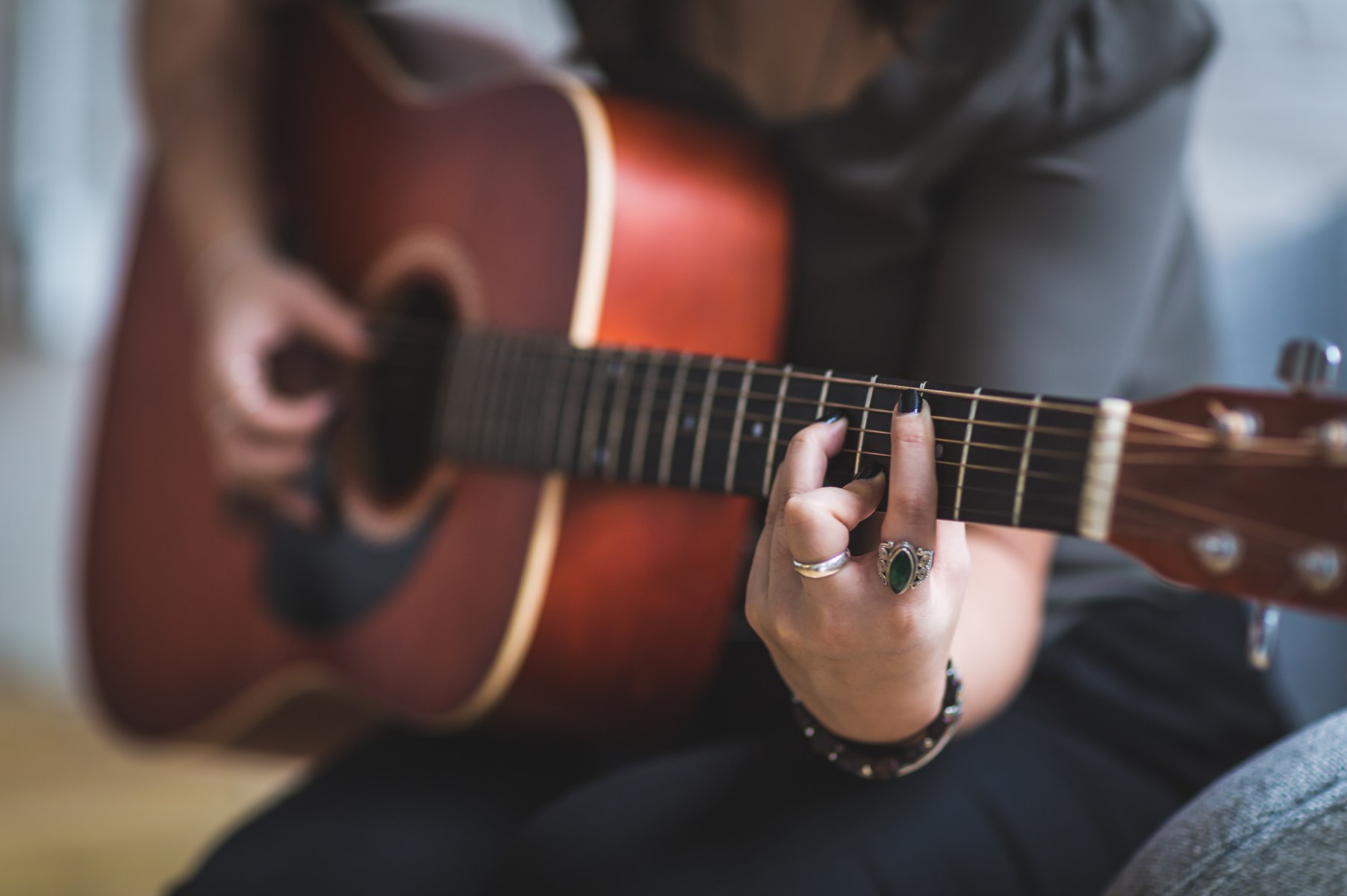 A female student learning chords in an acoustic guitar lesson in New Orleans.