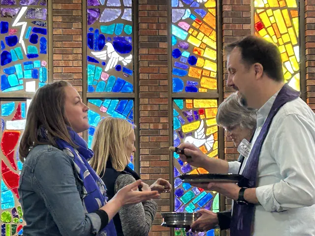 people receiving communion in front of stained glass windows