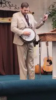 Evangelist Jonathan Cooper playing the banjo at a baptist church with need for revival preaching ministry