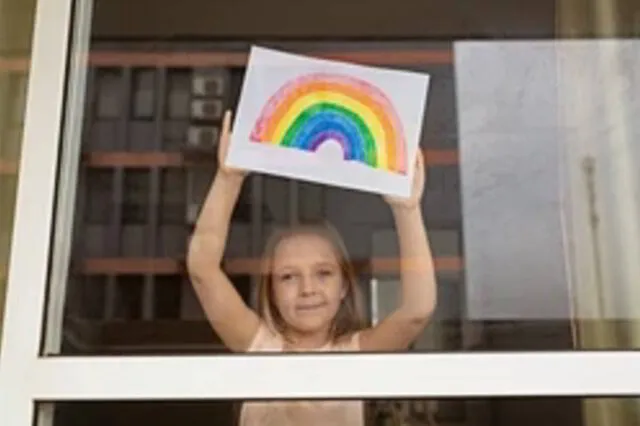 Happy child holding drawing in window