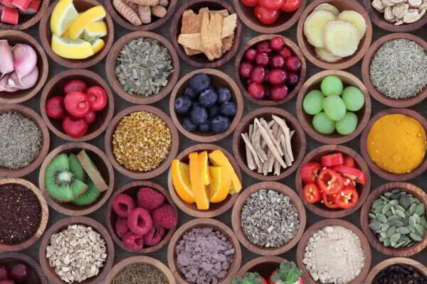 Assorted spices, herbs, and fresh fruit displayed in wooden bowls.