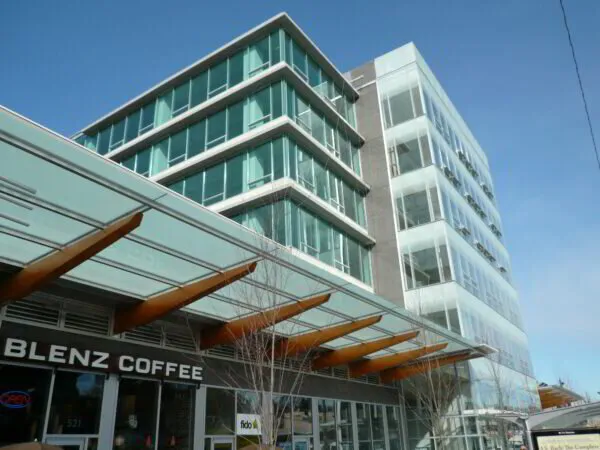Modern multi-story building with glass facade above Blenz Coffee shop on a clear day.