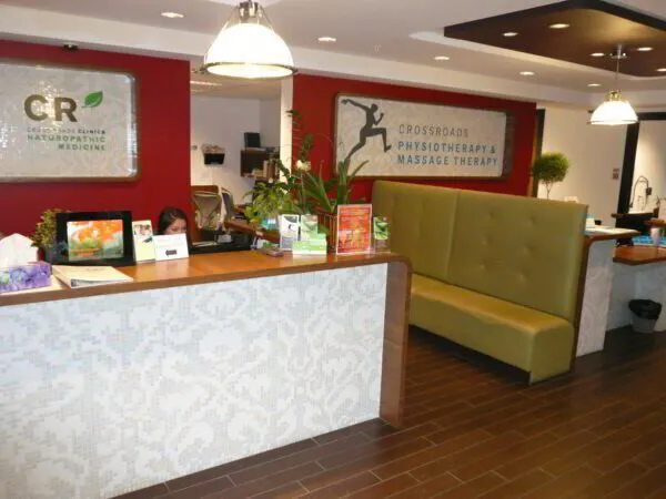 Reception area of Crossroads Physiotherapy & Massage Therapy clinic with red walls, seating, and pendant lighting.