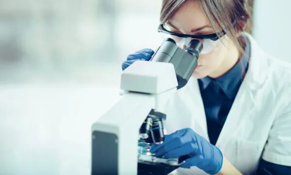 Female scientist using a microscope in a laboratory setting.