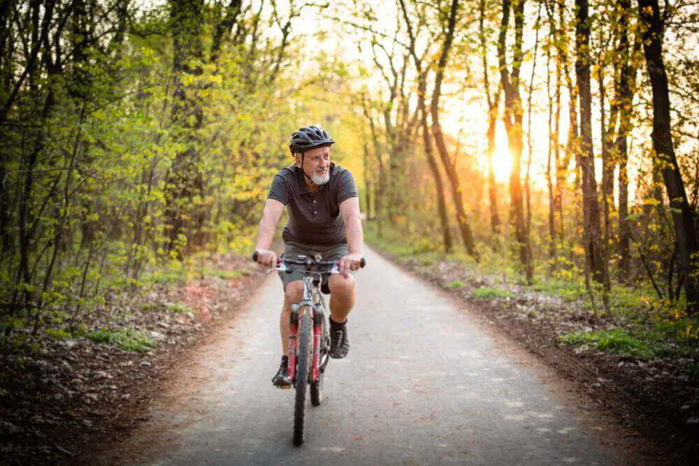 Person cycling on a forest trail at sunset.