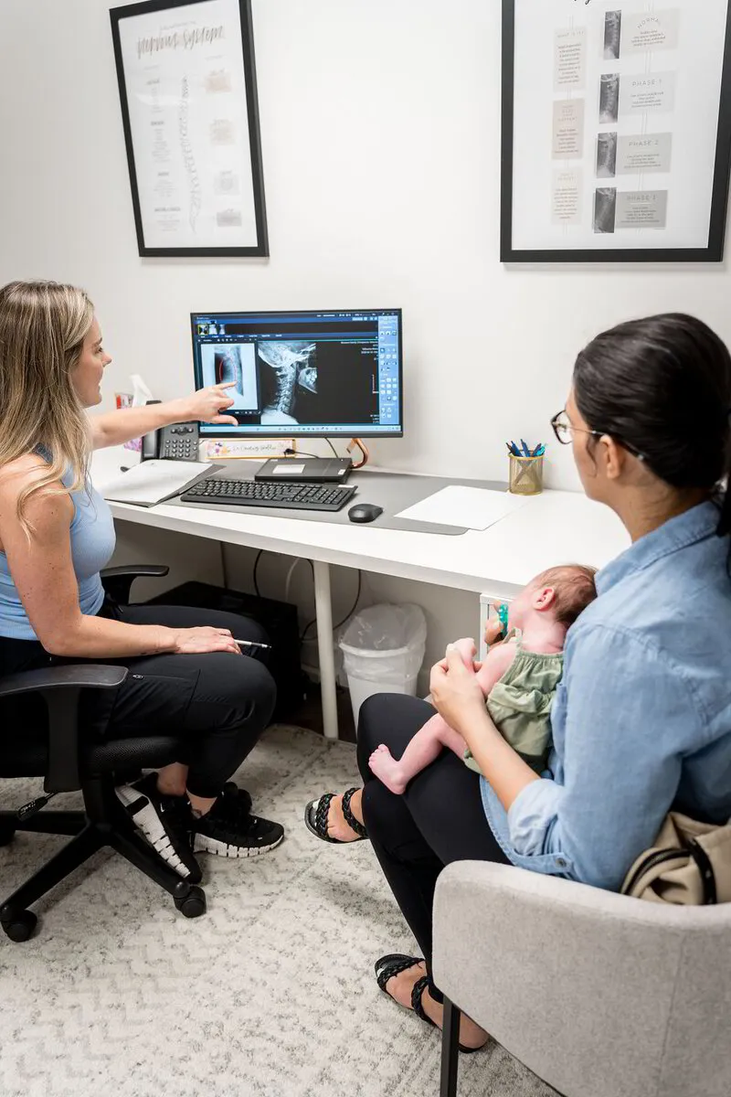 A doctor reviewing results on screen with a mom and her newborn