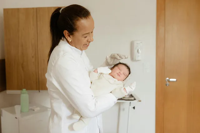 Chiropractor holding an infant. Good in a Room works with chiropractors on marketing to a niche.