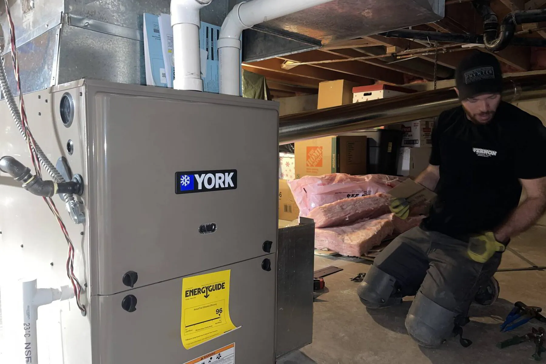HVAC technician installing a new furnace in a crawl space