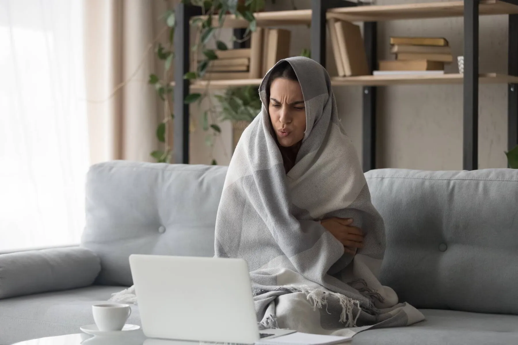 Woman cold in her home wearing a blanket