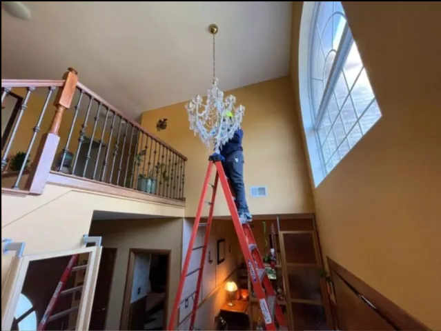 Man Cleaning Chandelier over stairwell