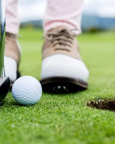 close up of a golfer putting a ball into a hole