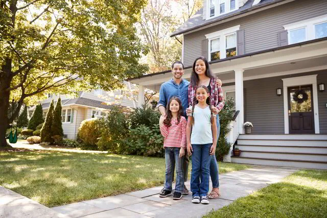 Family standing proudly in front of their home, secure with their mortgage protection policy