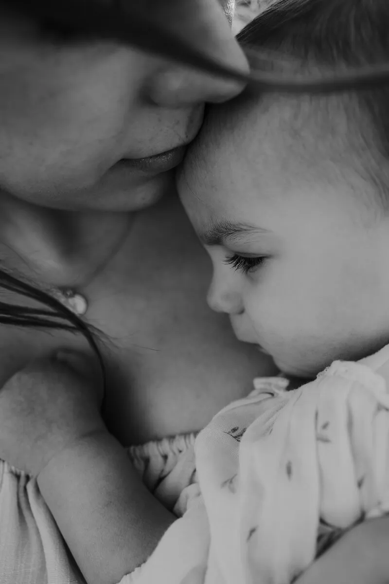 Moderskapsfotografering med en mamma som håller om sin 1-åring tätt intill 