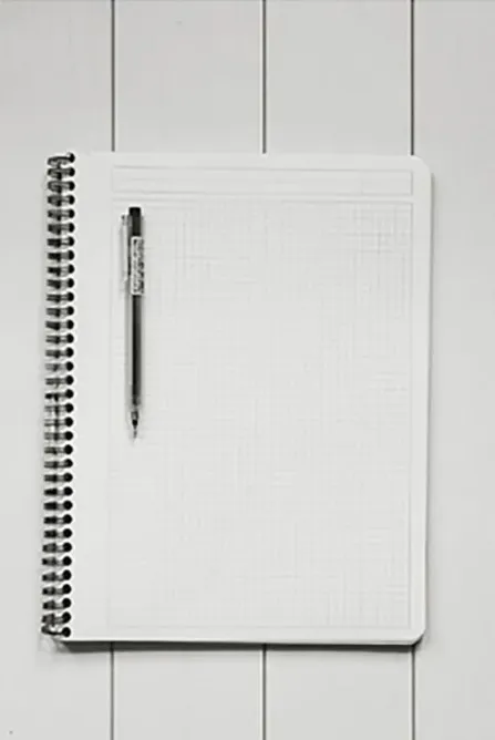 ringed notepad sitting open to a blank page with a pen sitting on flat tabletop