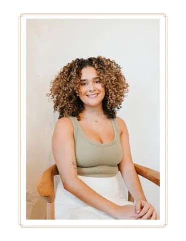 Luci McElroy, a stylist at Midtown Curls, seated gracefully in the salon, her friendly demeanor inviting clients to experience her styling skills in Reno, NV.