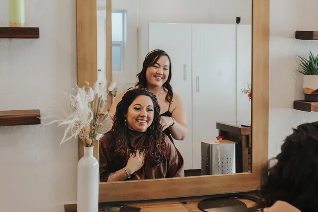 A stylist and client share a joyful moment during a first-time curly haircut at Midtown Curls salon in Reno, NV, reflecting the salon's commitment to creating an uplifting and welcoming experience.
