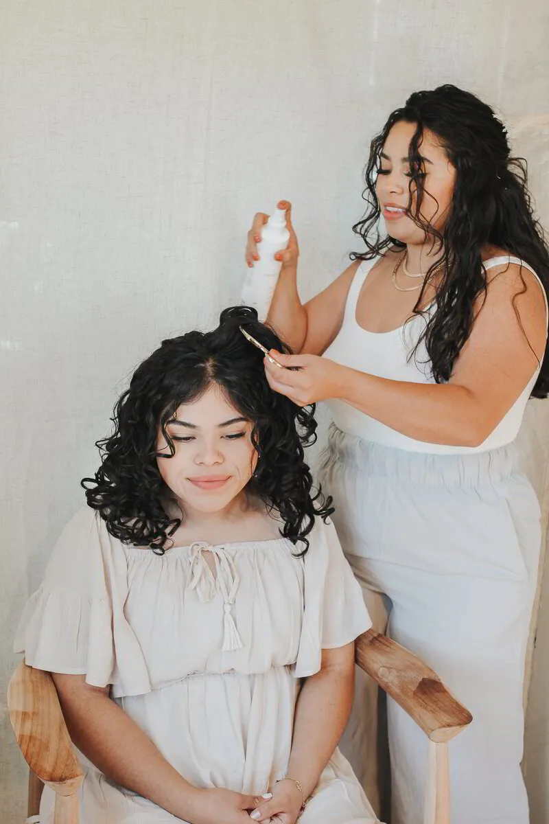 In a serene Reno, Nevada salon, Julie Guerrero of Midtown Curls showcases her expertise as she styles a client's voluminous curly hair, applying product with precision and care.