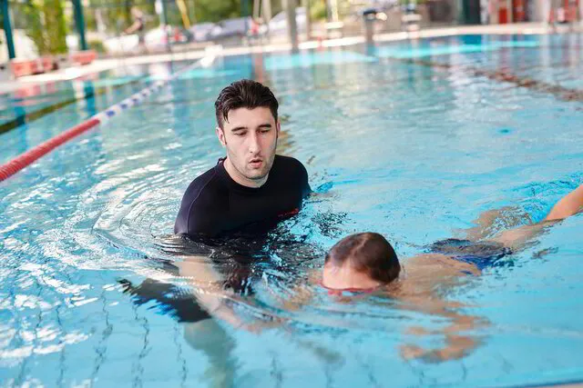 Schwimmlehrer trainiert tauchendes Kind im Wasser