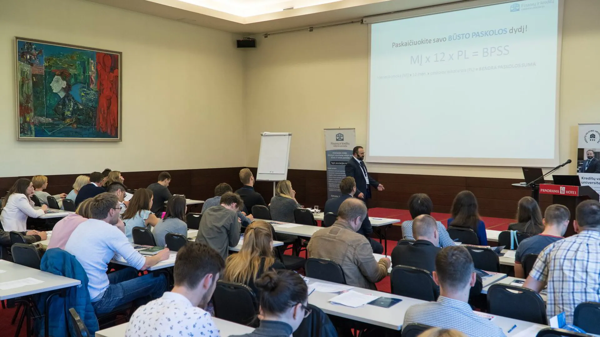 FIKVA mokymų dalyviai dirba su savo finansų planais prie stalų