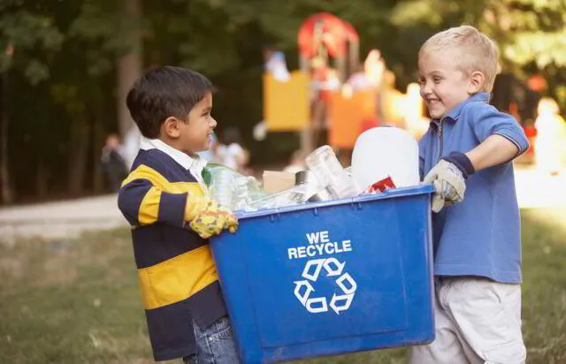 2 boys carrying a box of recycling