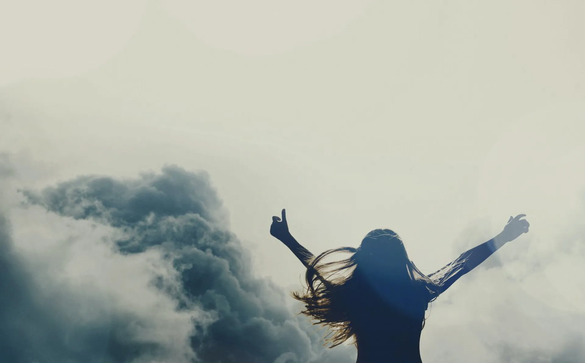woman with hands up around clouds